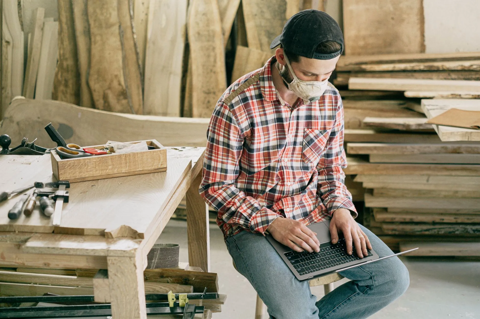 A furniture maker in his workshop with a laptop